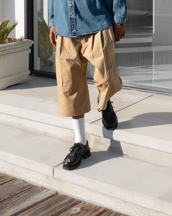 Person standing on a modern patio with a view of a building interior.